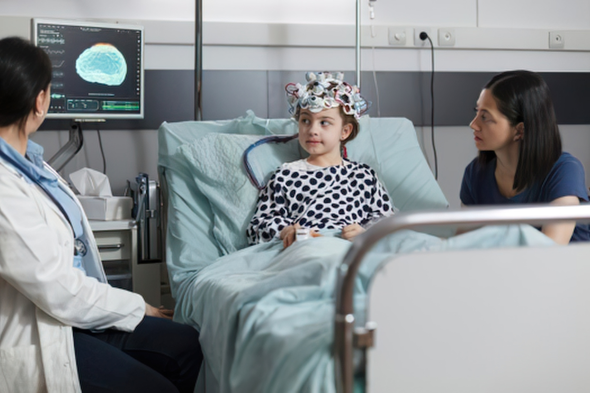 Young patient wearing an EEG diagnostic cap during clinical brain monitoring alongside medical professionals
