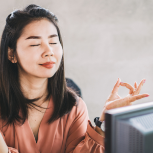 Professional engaging in mindfulness and biofeedback stress-reduction training in front of a computer screen