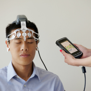 Patient wearing a non-invasive forehead neuro-sensor connected to a mobile clinical monitoring device