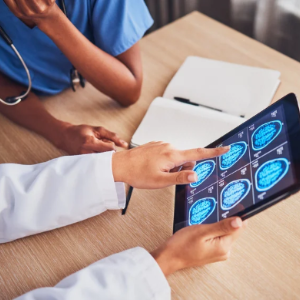 Medical professional pointing to brain scan results on a digital tablet during a clinical consultation